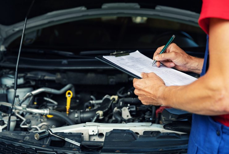 car maintenance and repair - mechanic writing checklist paper on clipboard